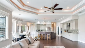A spacious living area with a large sofa, a dining table, and a kitchen with a central island.