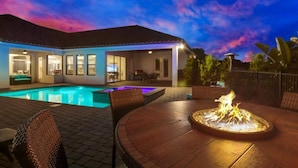 A poolside area with a fire feature, outdoor seating, and a covered patio.