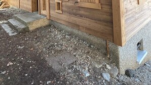 A wooden building with multiple windows and doors, some with shutters. There are steps leading to the entrance. - Large chalet La Clusaz - Exceptional view of the Aravis mountains in the Balme sector (La Clusaz)