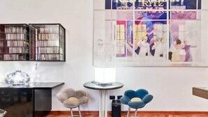 A modern room with a black bookshelf, a round table with a lamp, and two chairs with a unique design. - LuxRent Loft Lagrange Sauna Gym (Torino)