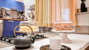 A kitchen with a gas stove, a kettle, a coffee machine, and a pastry display. - LuxRent Loft Lagrange Sauna Gym (Torino)