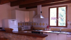 A kitchen with white cabinets, a microwave, a stove, and a window with a view of greenery. - Spacious 3 Bed Gite, Aude, Pool, Hot Tub, Free Wi-fi, Games Room, Pet-Friendly! (Arques)