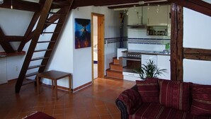 A spacious living area with a wooden staircase, a kitchen in the background, and a red sofa. - NEW !  Spacious apartment on 2 floors for 2-3 people (Baiersbronn)