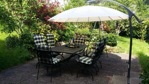 A patio with a table and four chairs, an umbrella, and a hanging chair. - NEW !  Spacious apartment on 2 floors for 2-3 people (Baiersbronn)