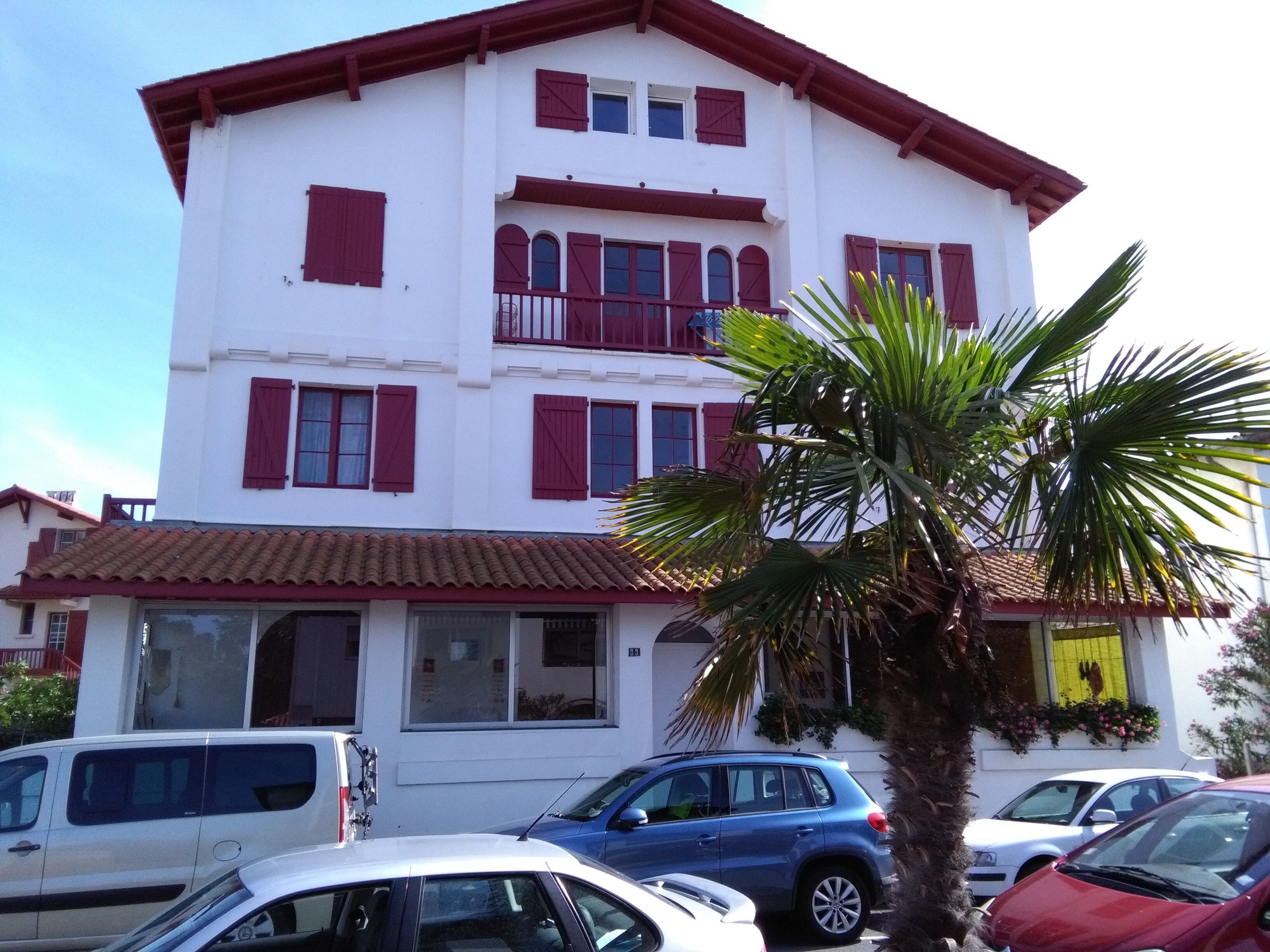 A multi-story building with red shutters and a tiled roof.