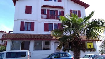 A multi-story building with red shutters and a tiled roof.