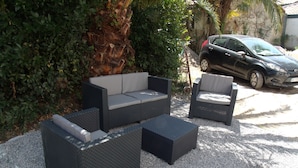 An outdoor seating area with a sofa and two chairs, surrounded by gravel and greenery. - Promo Aptn2 T3 and garden 50 meters from the beach  (Hendaye)