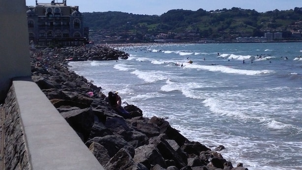 A coastal view with rocky shoreline, waves, and a distant building. - Promo Aptn2 T3 and garden 50 meters from the beach  (Hendaye)