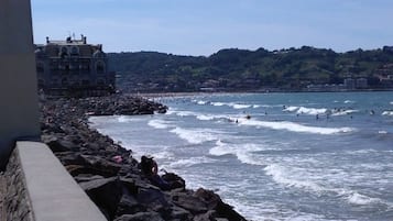 A coastal view with rocky shoreline, waves, and a distant building.