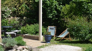 A garden patio with a table and chairs, a blue chair, and a planter with flowers. - Air-conditioned detached house 60m2 with garden (Sénas)