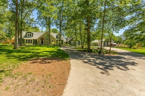 Een stenen huis met twee verdiepingen, een overdekte veranda en een verzorgd gazon.