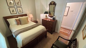 Quarto com cama, mesa de cabeceira, cômoda, cadeira e espelho.