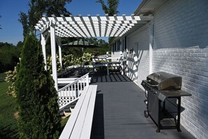 Un patio esterno coperto con barbecue, posti a sedere e una pergola.
