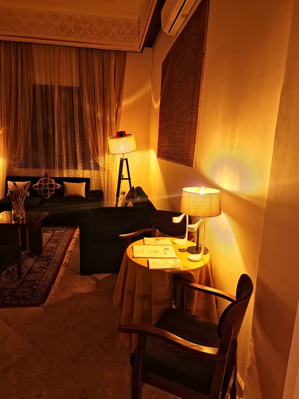 Una habitación de hotel acogedora con un sofá, una mesita con una lámpara y una silla.