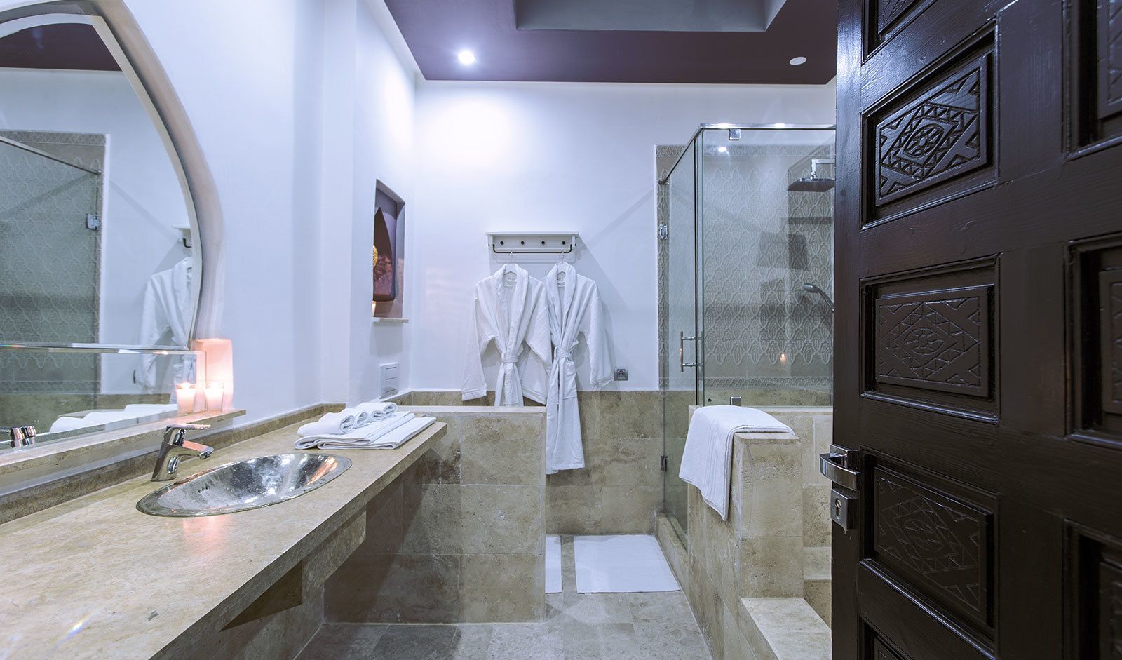 Un baño moderno con un espejo grande, un lavamanos, una ducha y un perchero para toallas.