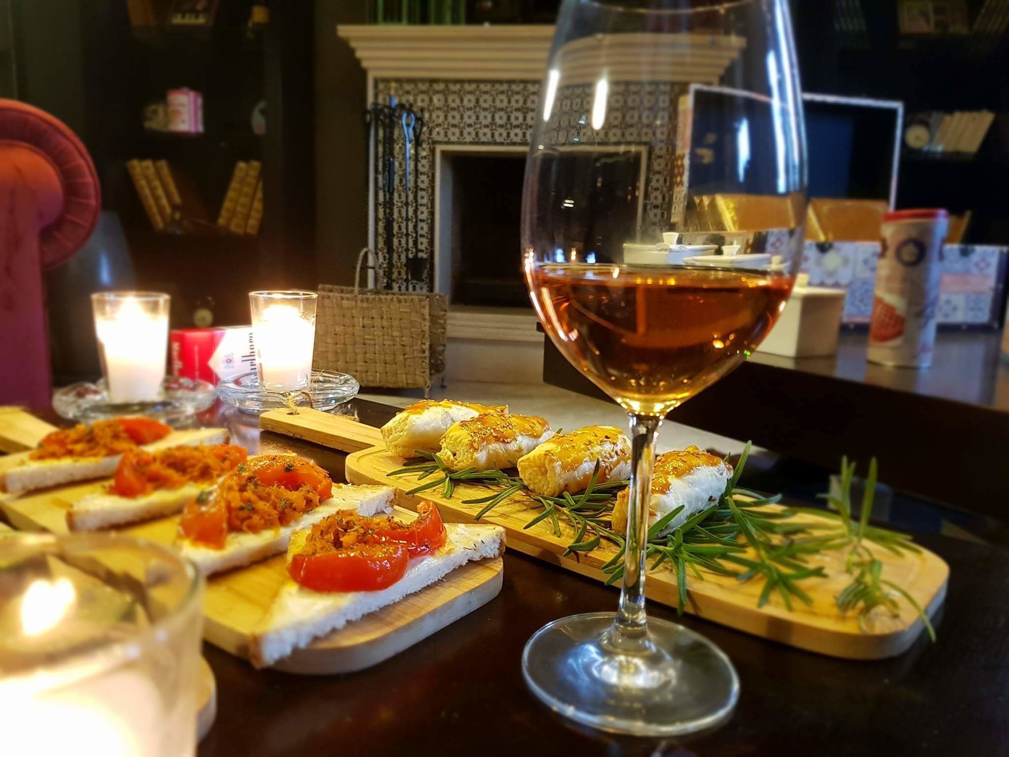 Ein Tisch mit verschiedenen Vorspeisen, einem Weinglas, Kerzen und einem Kamin im Hintergrund.