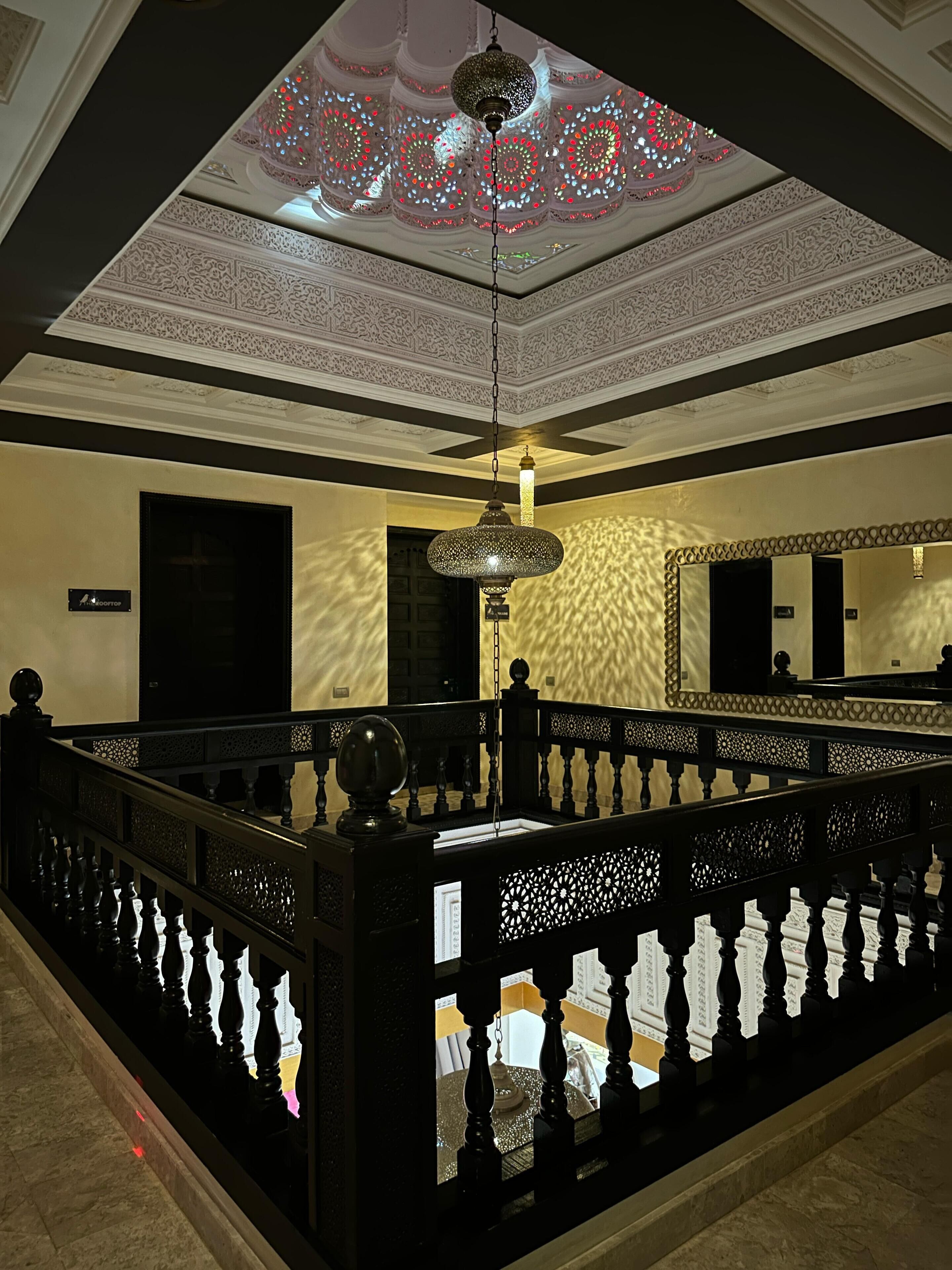 A grand lobby with ornate ceiling designs, a chandelier, and a reflective floor.