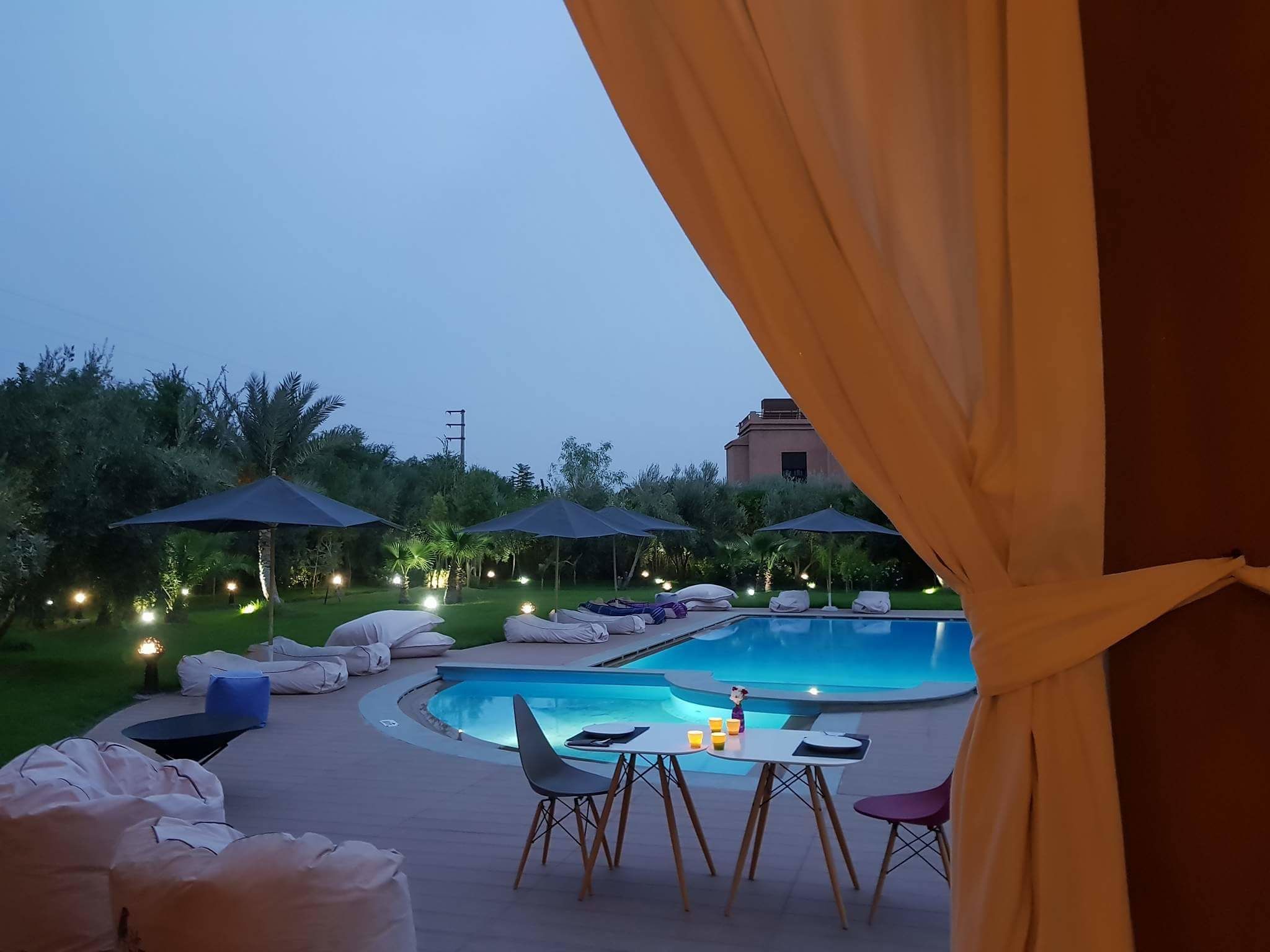Zona de piscina con sillones reclinables, sombrillas y una mesa con sillas.