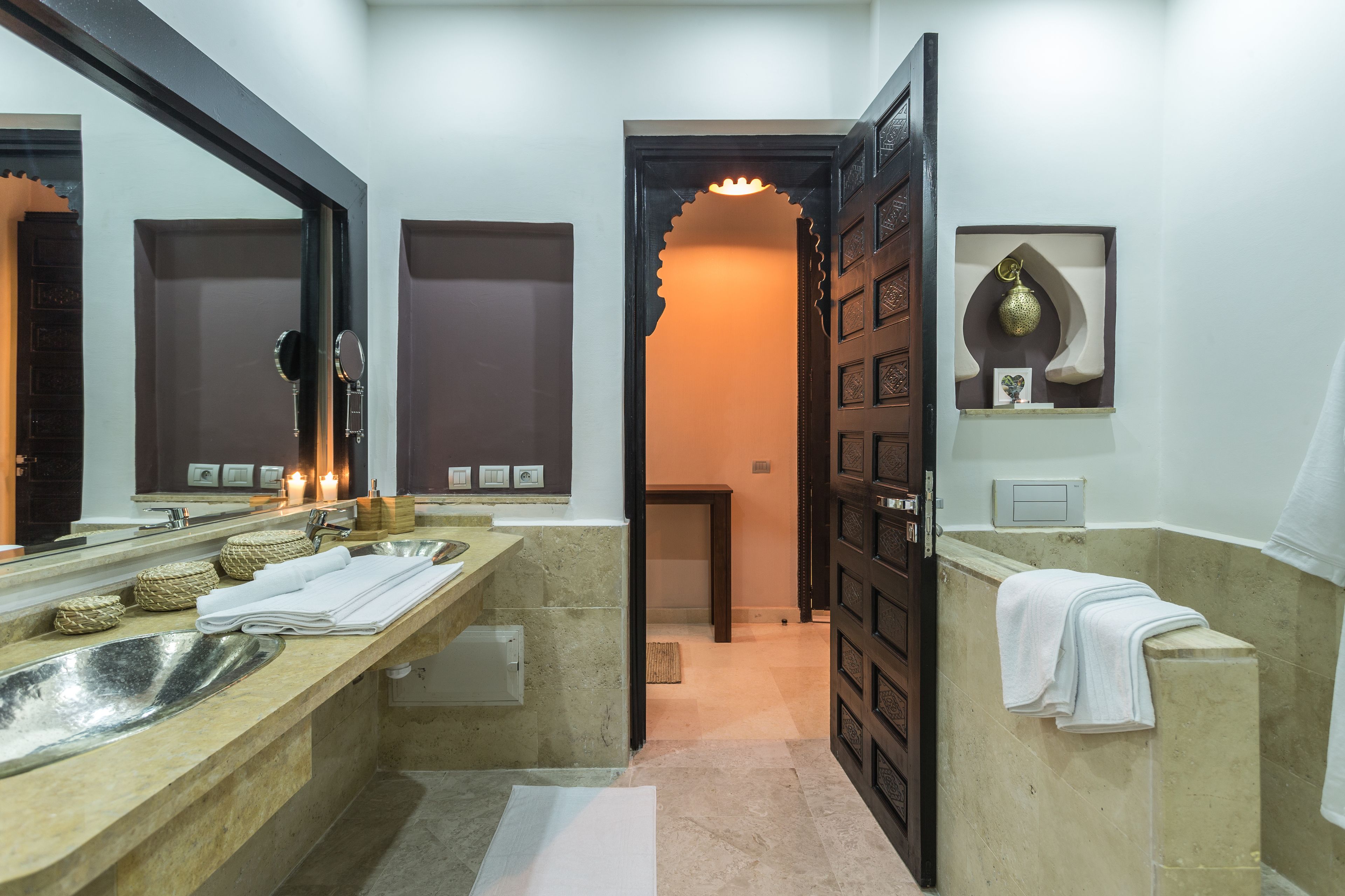 Casa de banho moderna com uma grande pia, espelho e porta decorativa.