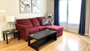 A modern living room with a red sectional sofa, a black coffee table, and two abstract paintings on the wall. - Cute and spacious single family home, pet friendly (Charlotte)