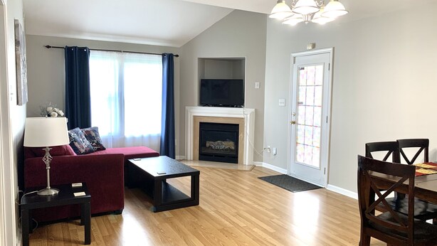 A living room with a sofa, a coffee table, a fireplace, a dining table with chairs, and a TV mounted on the wall. - Cute and spacious single family home, pet friendly (Charlotte)