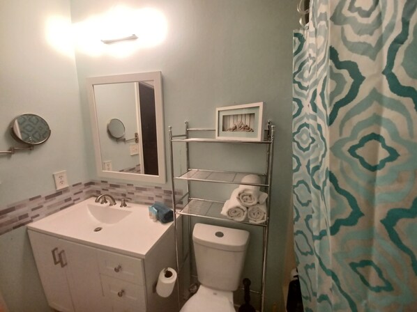Un baño con un lavabo blanco, un espejo, un inodoro y un perchero para toallas.