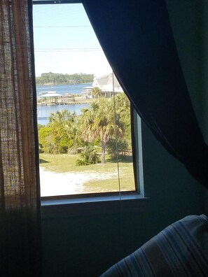 A room with a window overlooking a body of water, a dock, and some greenery. - Lagoon view within walking distance to the beach. One mile from the Hangout  (Gulf Shores)