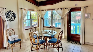 A dining area with a round table, four chairs, and a ceiling fan. - Sunset Beach "C3" - Beachfront, Breathtaking, Free Kayaks, Bikes & More! 🏖 (San Pedro Town)