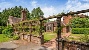 Une maison traditionnelle en briques, avec un chemin de jardin menant à un portail en bois.