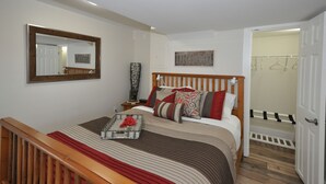 Un dormitorio ordenado con una cama de madera, una mesita de noche, un espejo y un armario.