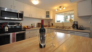 Una cocina moderna con electrodomésticos de acero inoxidable, una botella de vino y dos copas sobre la encimera.
