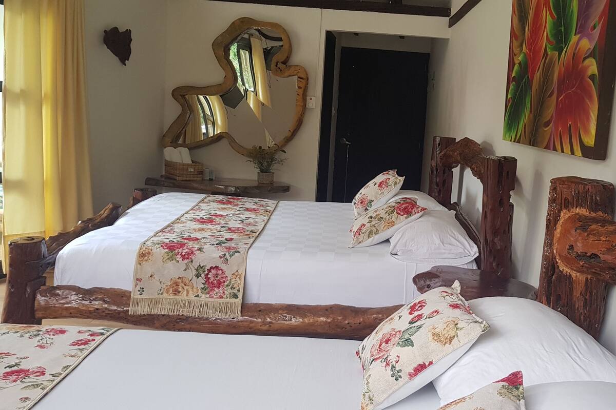 A bedroom with a wooden bed frame, white bedding, and a floral-patterned throw.