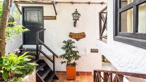 Un escalier menant à une porte portant l’inscription « Heliconia », avec une enseigne indiquant « Casa Hostal Antawara » et un panneau « Ruta de Evacuación ».