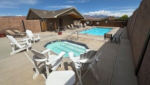 A backyard with a swimming pool, lounge chairs, and a building with a sloped roof. - THREE KING BEDS! Parking, CLEAN, Views, FIREPIT, Pool, Hot Tub, ACCESSIBLE! (Moab)