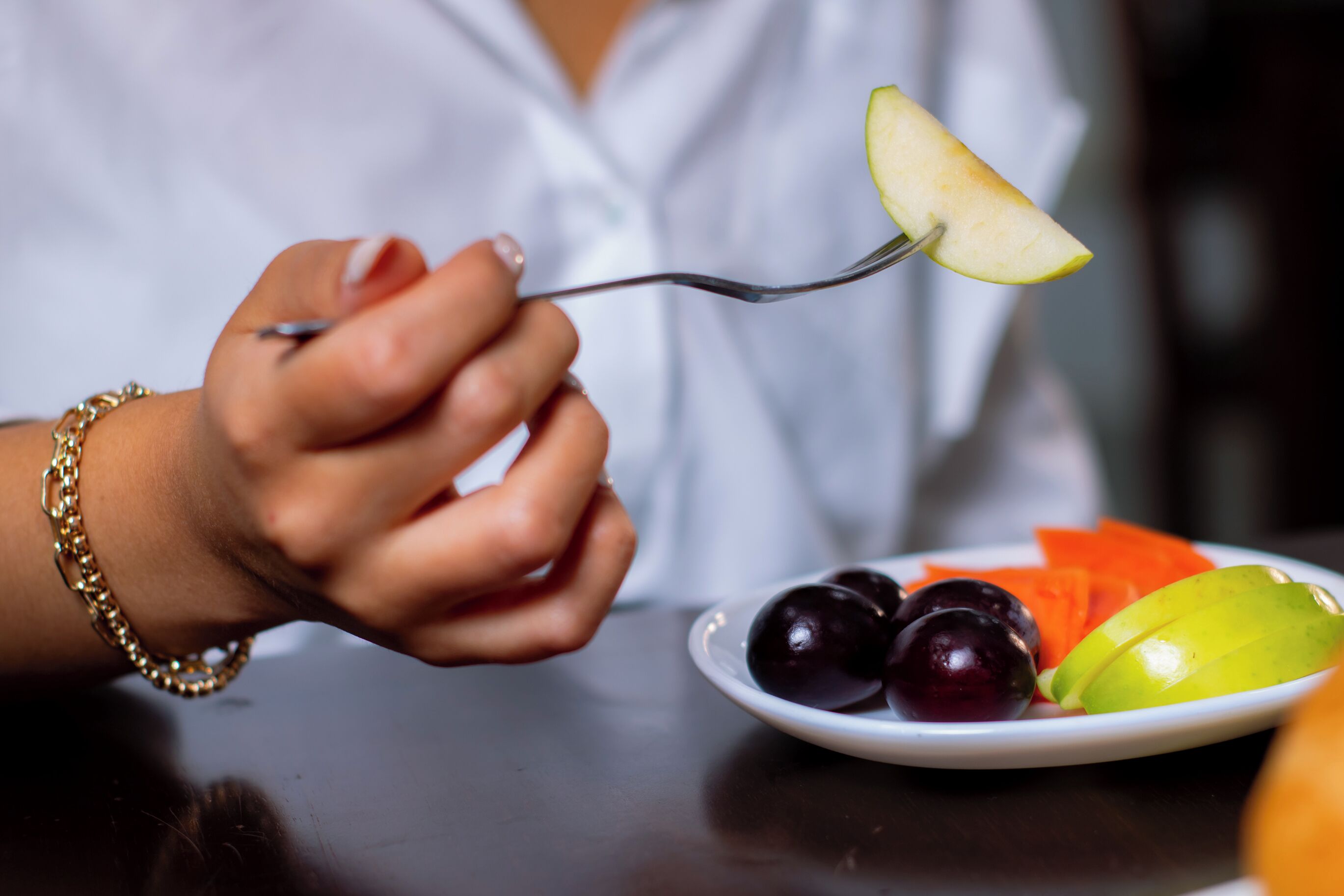 A person holding a fork with a slice of apple.