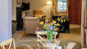 A dining area with a glass table, wicker chairs, and a vase of flowers. A deer antler is mounted on the wall above the table. - Very spacious rural retreat, walk to Crieff — Couples, Families, Pets Welcome. (Crieff)