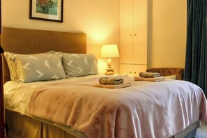 A neatly made bed with a headboard, a bedside lamp, and a folded towel on the bed. - Very spacious rural retreat, walk to Crieff — Couples, Families, Pets Welcome. (Crieff)