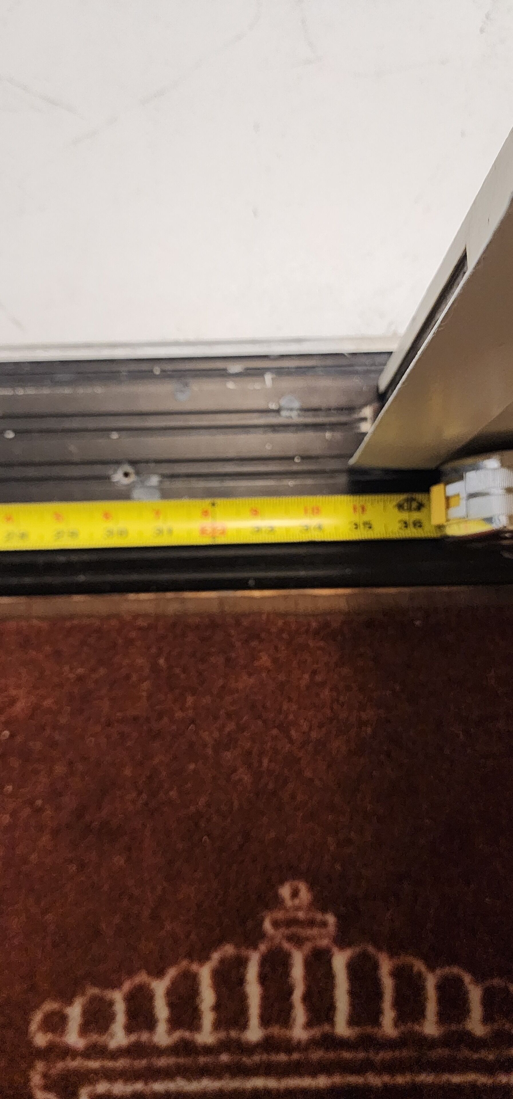 A carpet with a crown design, a measuring tape, and a metal structure.