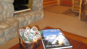 A log cabin interior with a stone fireplace, a television, and a book on a table.