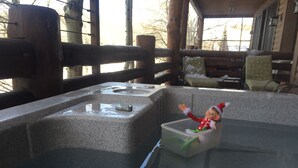 A wooden cabin interior with a stone basin and a plastic container with a toy figure.