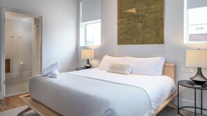 Un dormitorio moderno con una cama grande, lámparas de noche y un ventanal amplio.