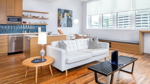 Una cocina moderna con microondas, armarios de madera y un comedor con sofá blanco y mesa.