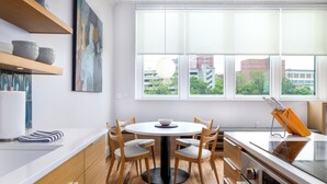 Una cocina moderna con una mesa redonda para comer, sillas de madera y un horno empotrado.