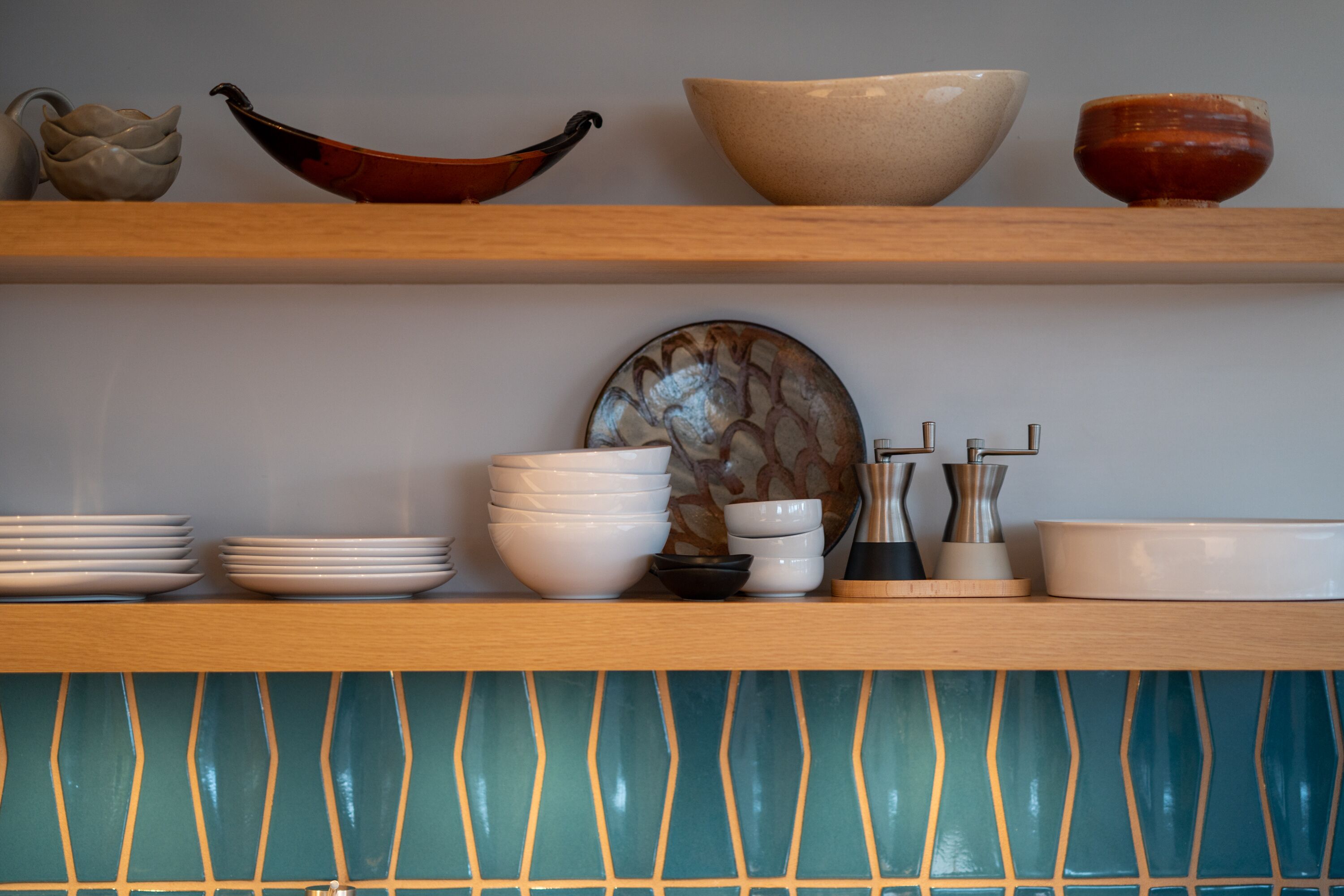 A kitchen shelf with various bowls, plates, and a decorative plate.