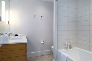 Une salle de bain moderne avec un lavabo blanc, un meuble-lavabo en bois, des toilettes et une baignoire.