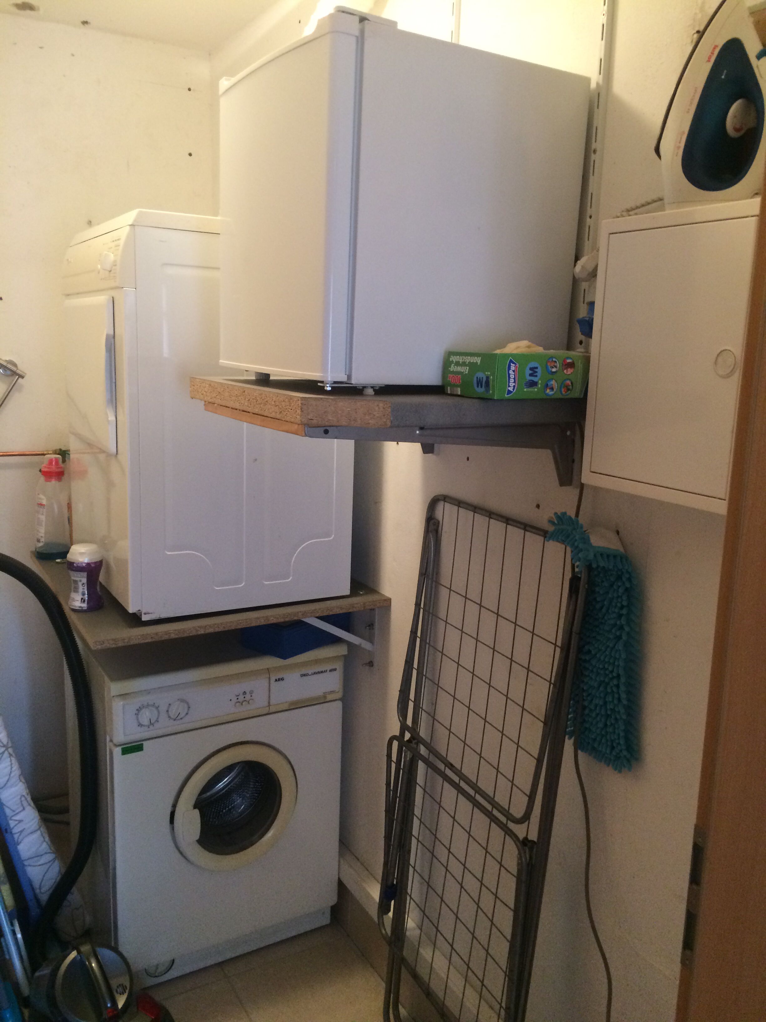 A compact laundry room with a washing machine, a dryer, and a drying rack.
