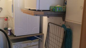 A compact laundry room with a washing machine, a dryer, and a drying rack.