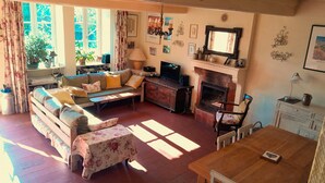 A cozy living room with a sofa, a television, a fireplace, and a dining table.