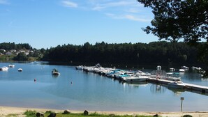 Una marina con barcos amarrados, una playa de arena y un área boscosa al fondo.