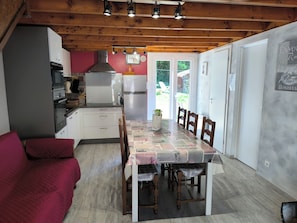 A kitchen with wooden beams, a dining table with chairs, and a refrigerator.